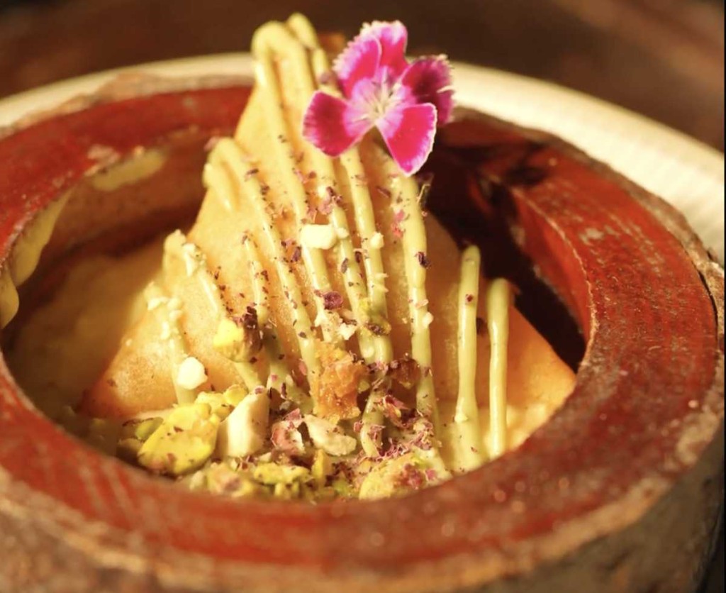 Artisan dessert samosa with pistachio and flower garnish