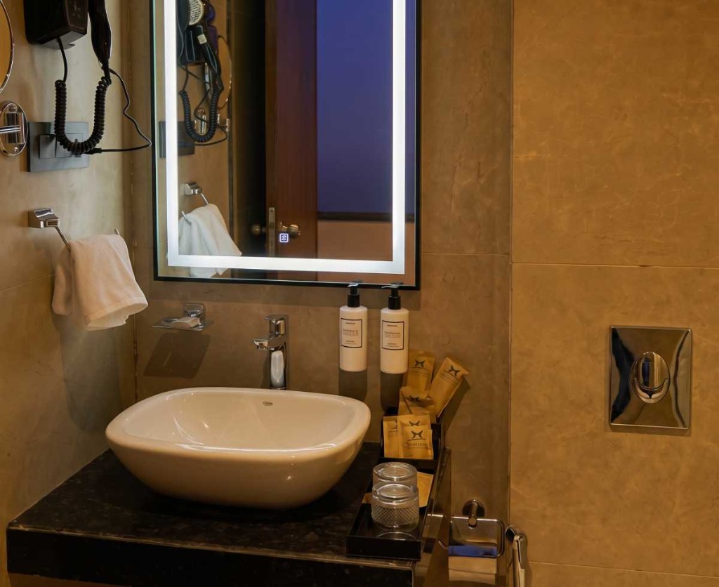 2 BHK villa bathroom with marble vanity and lit mirror